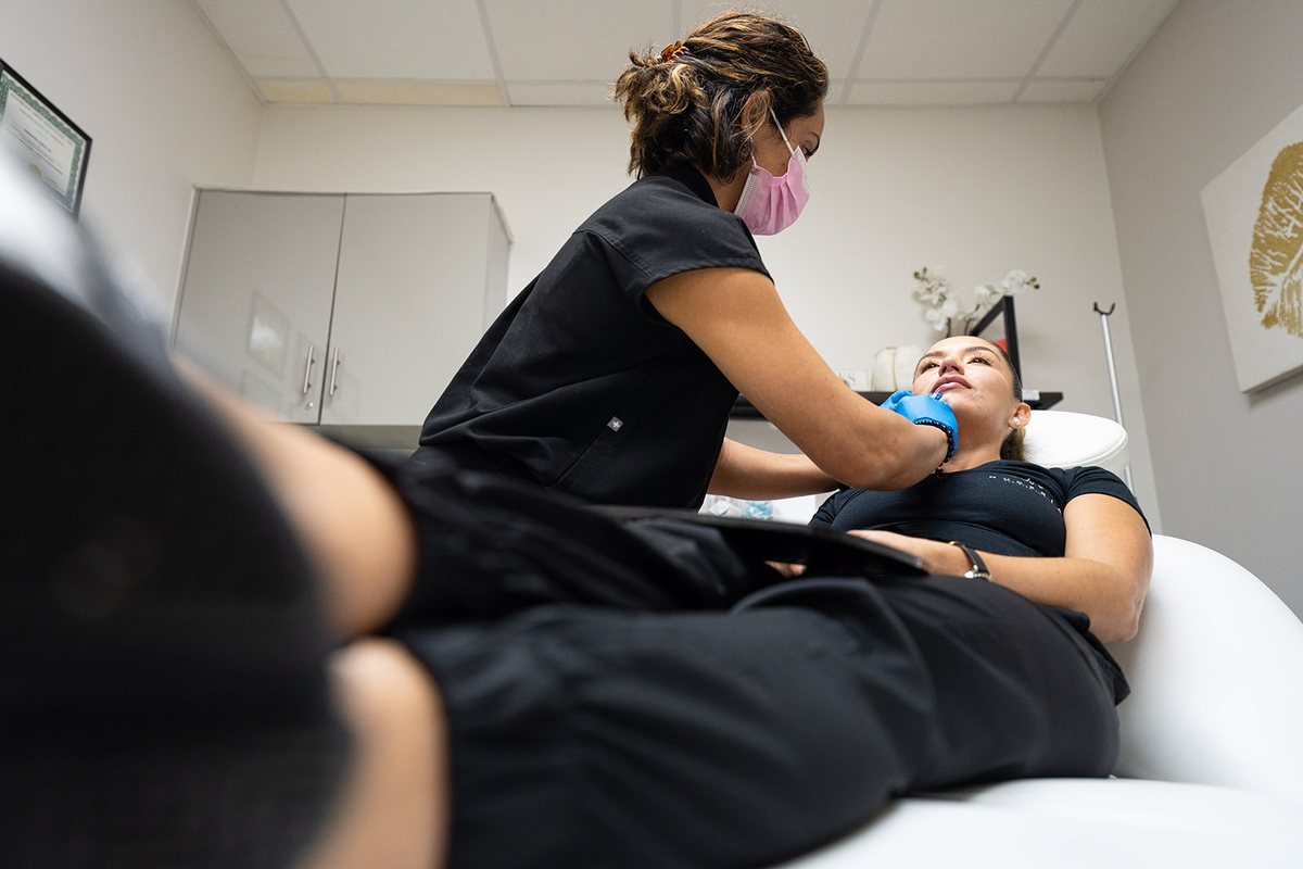 A masked provider leans over a patient during a treatment