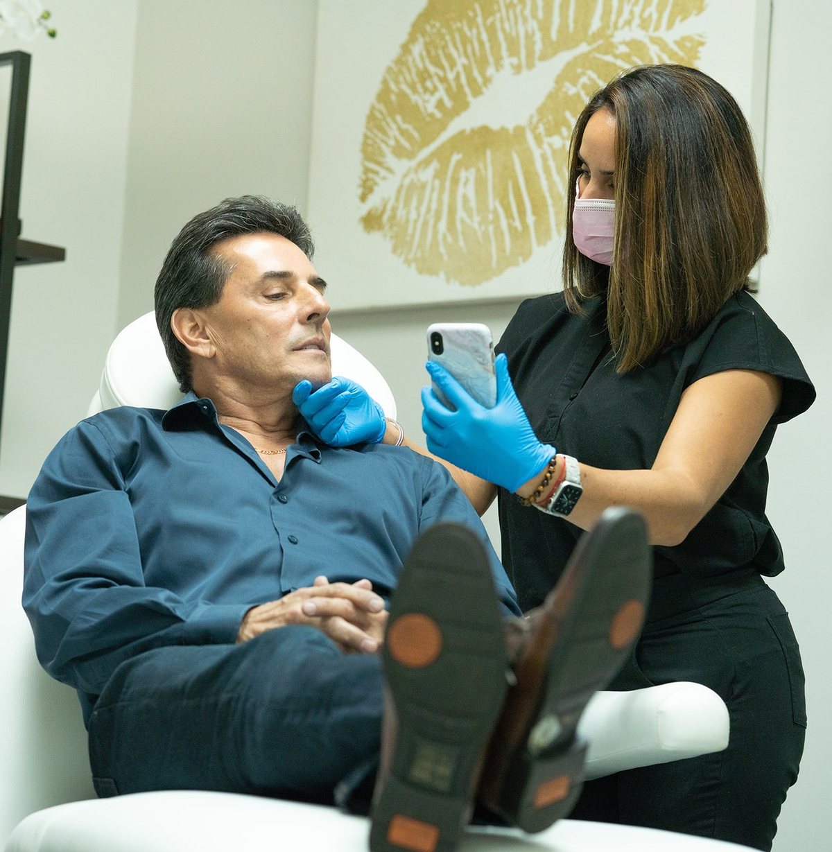 A provider shows a patient something on a phone in a treatment chair